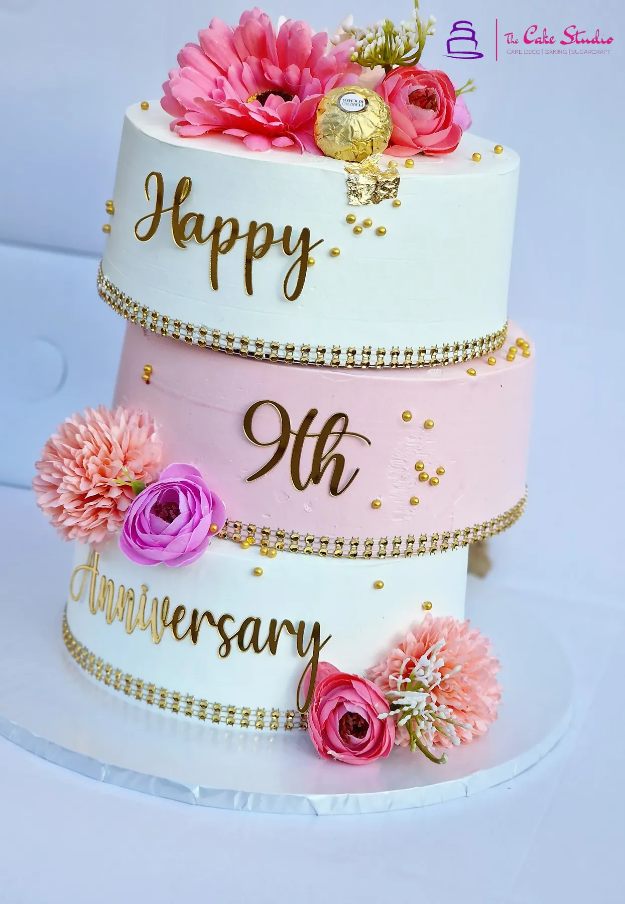 A simple, elegant single-tier anniversary cake with floral cascade and a script topper, baked by The Cake Studio Harare