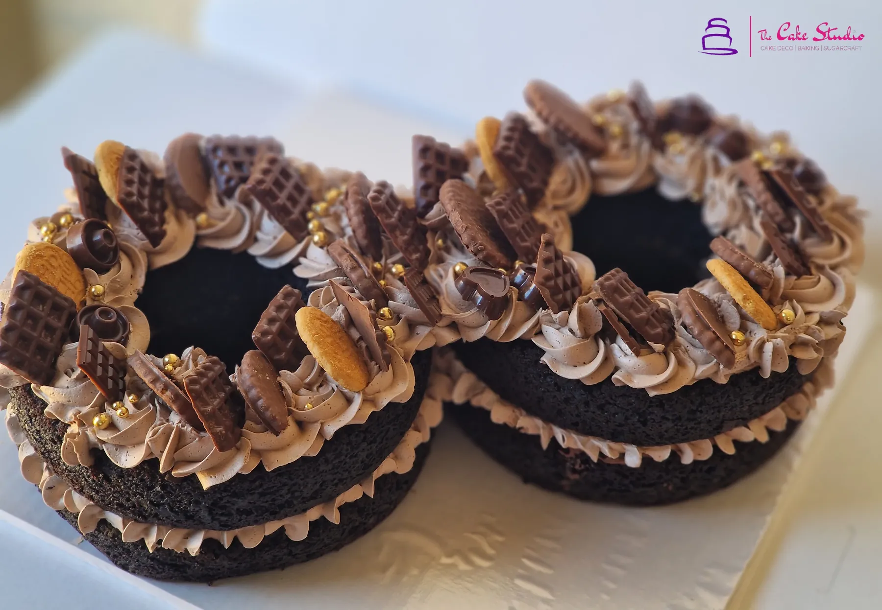A two-piece Death by Chocolate cake topped with KitKat fingers, Oreos, Bourbon biscuits, chocolate buttercream rosettes and gold pearls, baked by The Cake Studio Harare