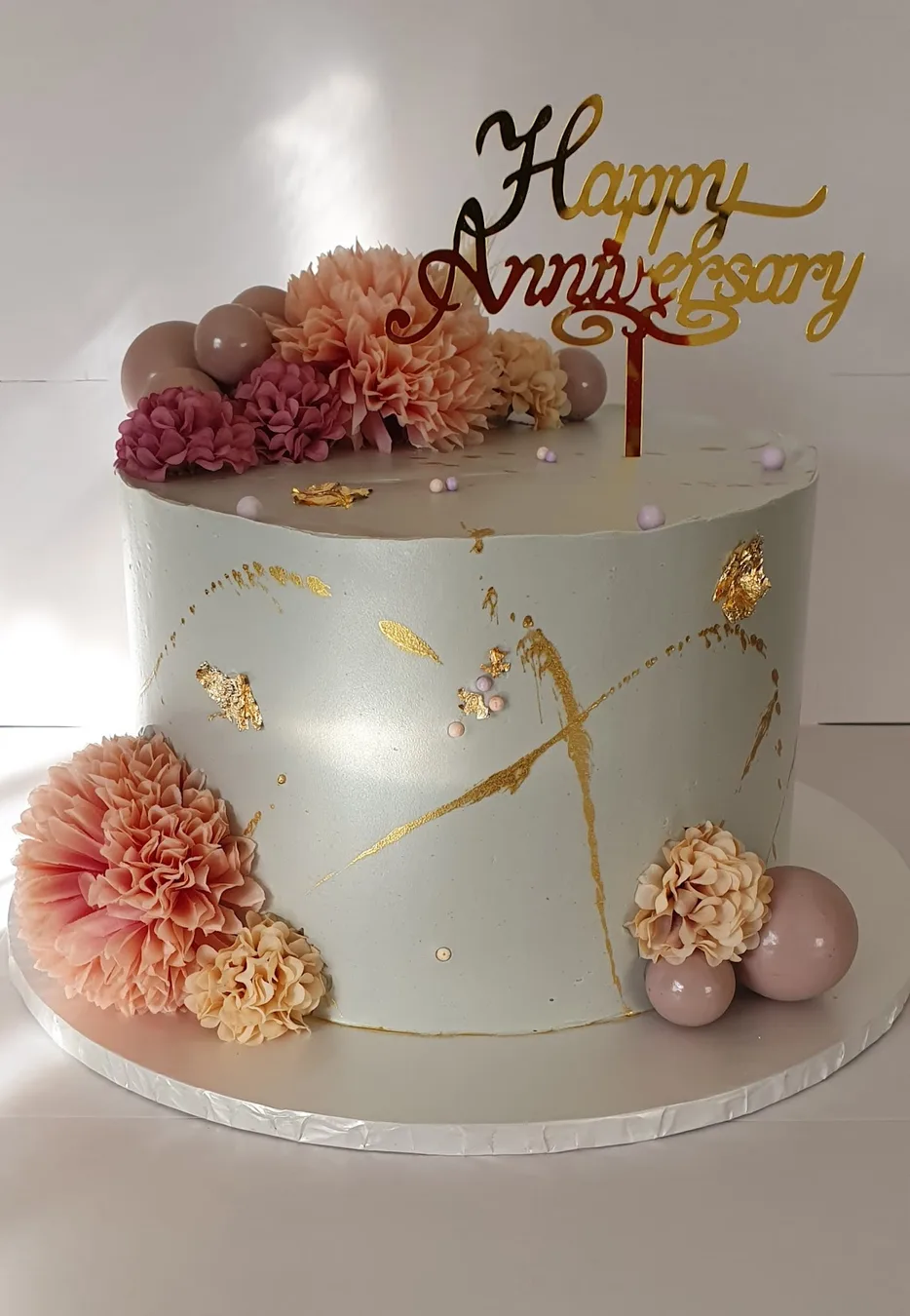 A white and gold anniversary cake with dried flowers