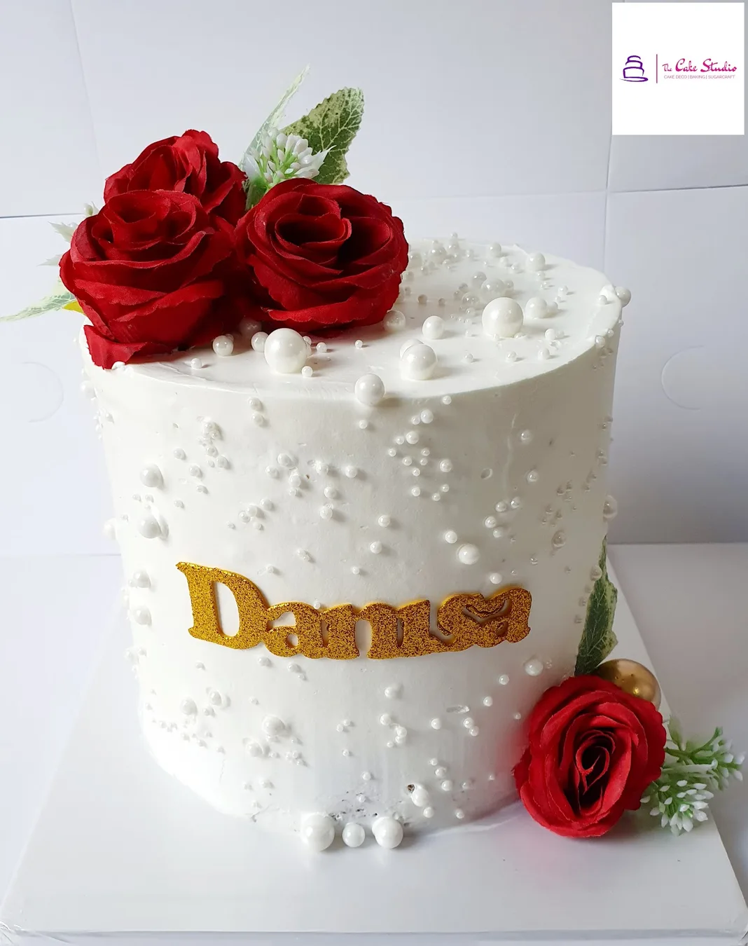 A white celebration cake with red roses