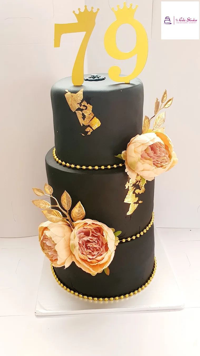 A black and gold two-tier milestone cake with roses