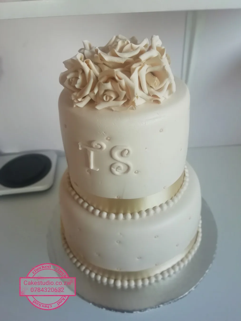 A two-tier ivory wedding cake with sugar roses