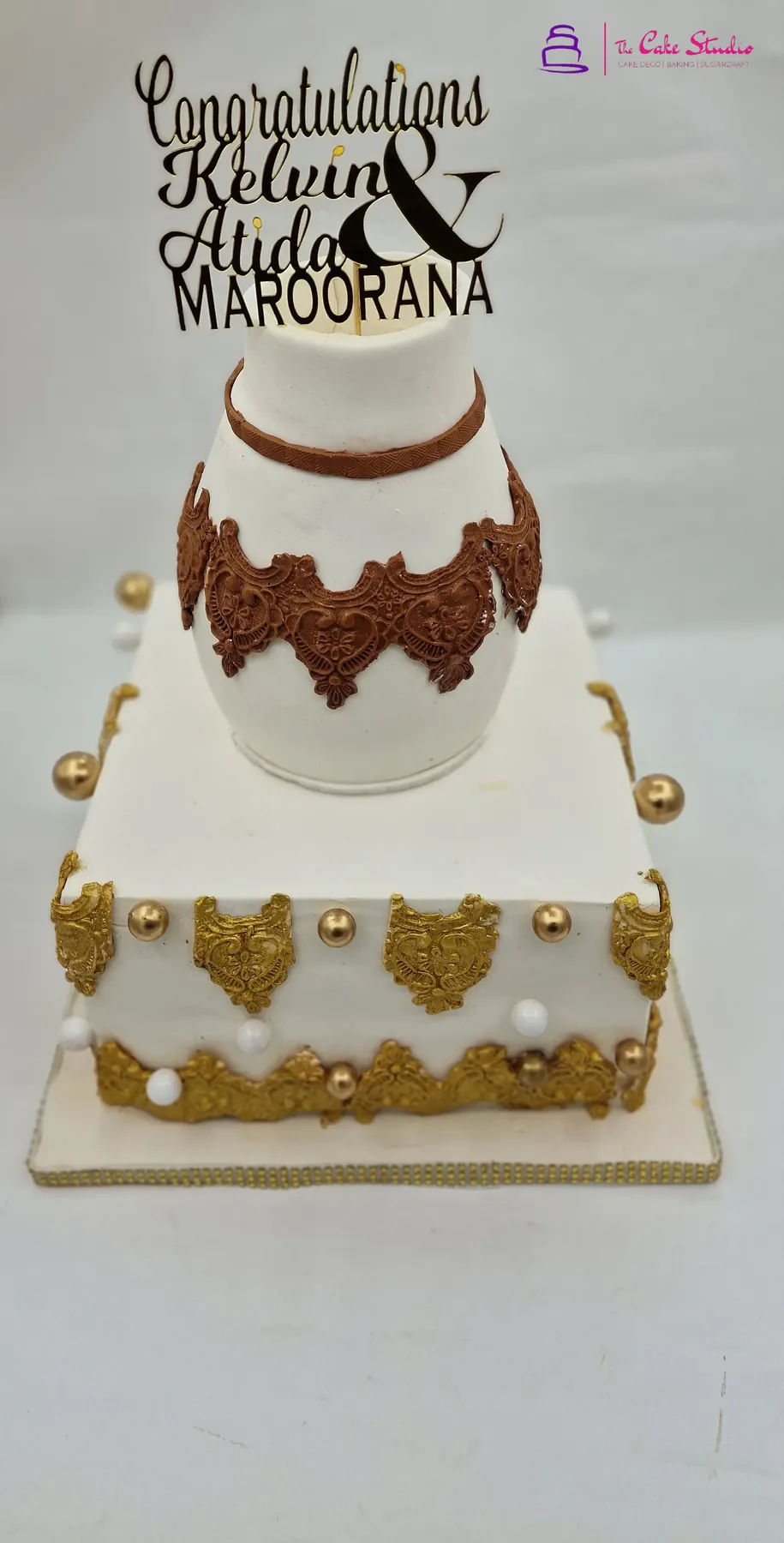 A Roora Day cake in cream and gold with hand-piped detail